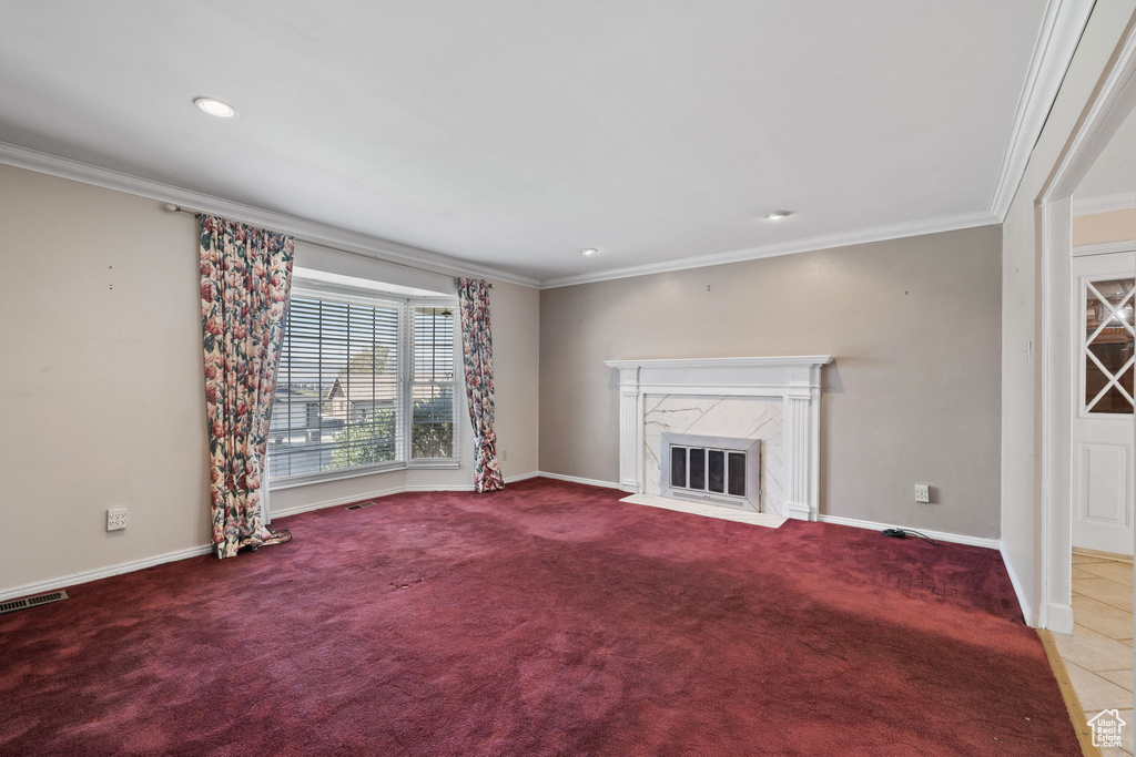 Unfurnished living room featuring crown molding, a fireplace, and carpet floors