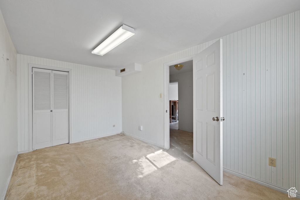 Unfurnished bedroom featuring light carpet and a closet