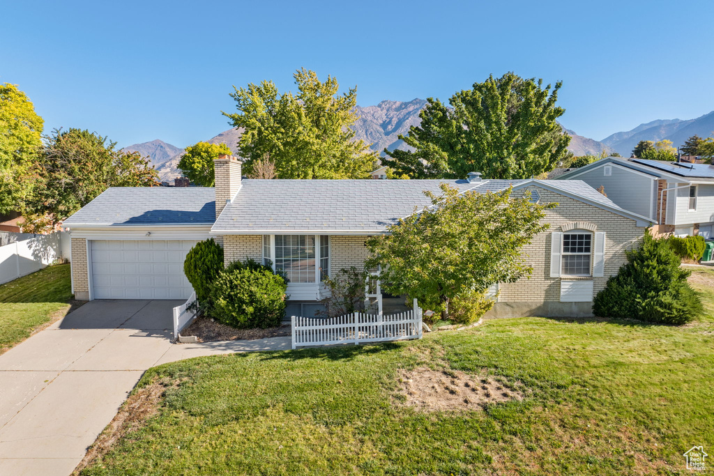 Single story home featuring a front yard, a garage, and a mountain view