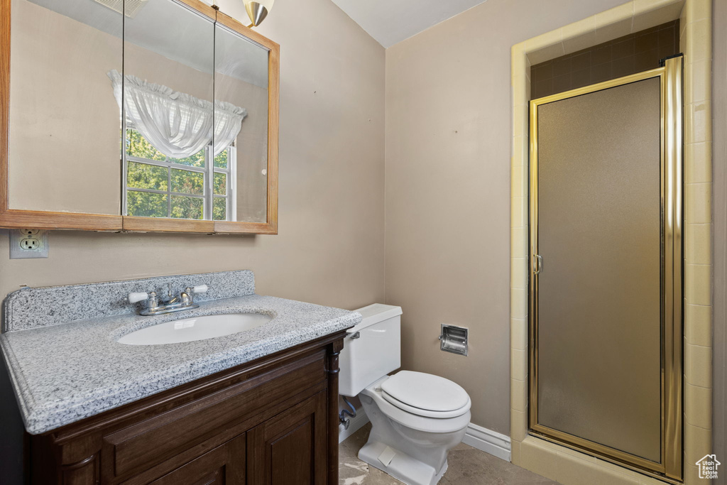 Bathroom with toilet, tile patterned flooring, vanity, and a shower with door