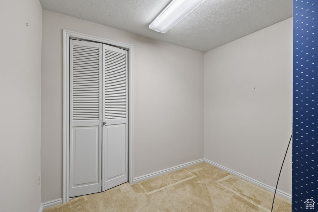 Unfurnished bedroom featuring a textured ceiling, carpet flooring, and a closet