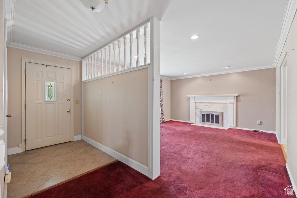 Carpeted foyer featuring crown molding and a fireplace