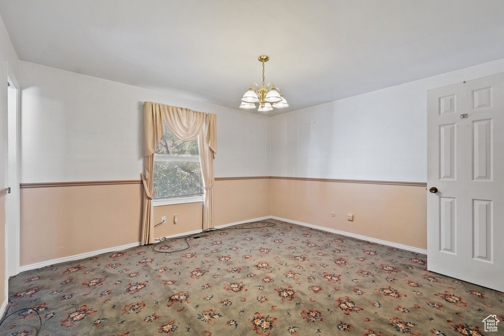 Unfurnished room featuring a notable chandelier and carpet floors