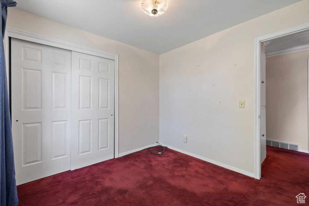 Unfurnished bedroom featuring a closet and dark carpet