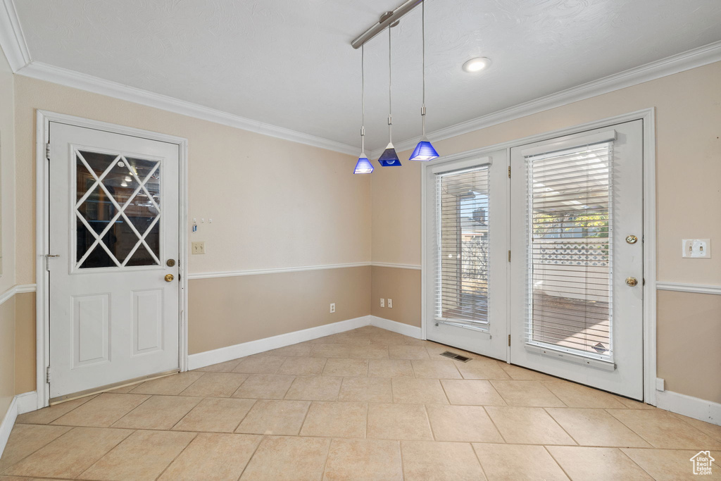 Doorway to outside with ornamental molding and light tile patterned floors