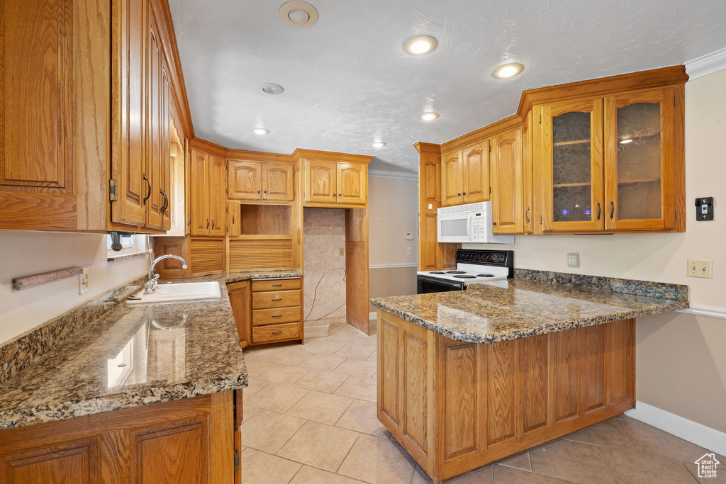 Kitchen featuring white appliances, dark stone countertops, ornamental molding, and sink