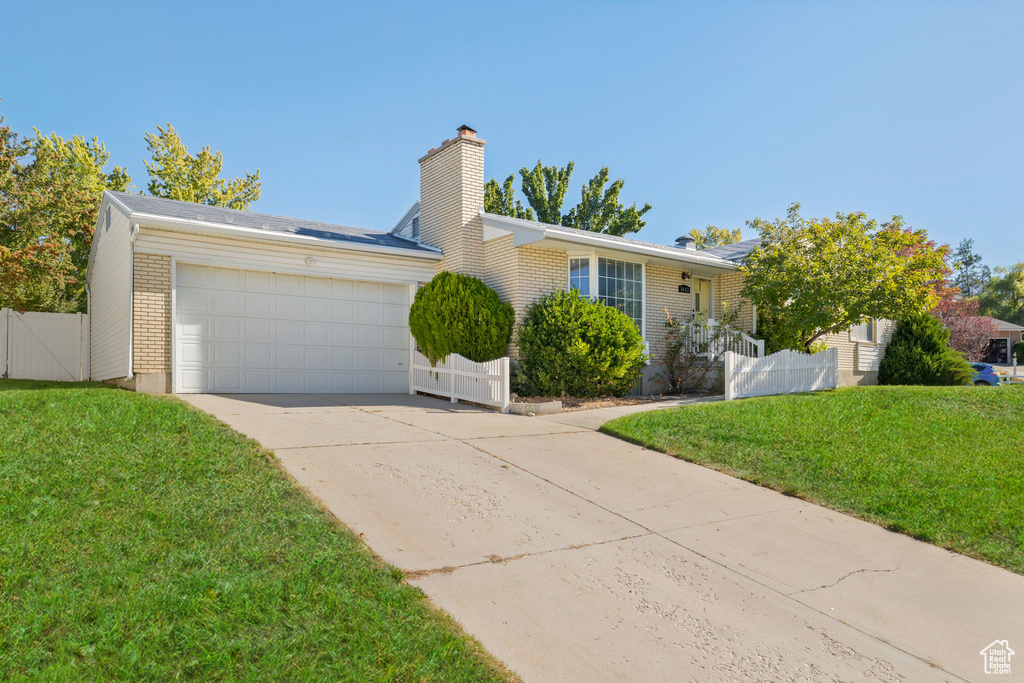 Ranch-style house with a front yard and a garage