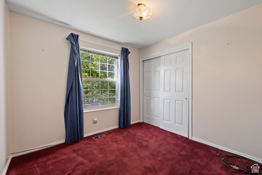 Unfurnished bedroom featuring dark carpet and a closet