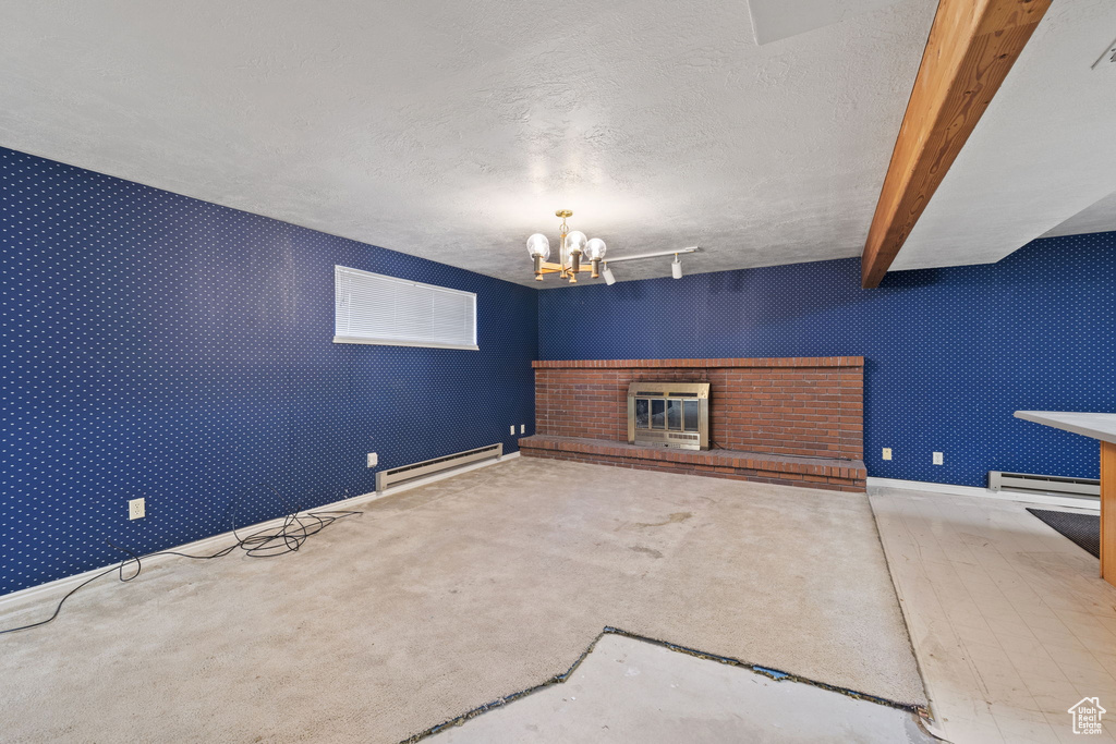 Unfurnished living room with beam ceiling, a textured ceiling, a baseboard radiator, and a brick fireplace