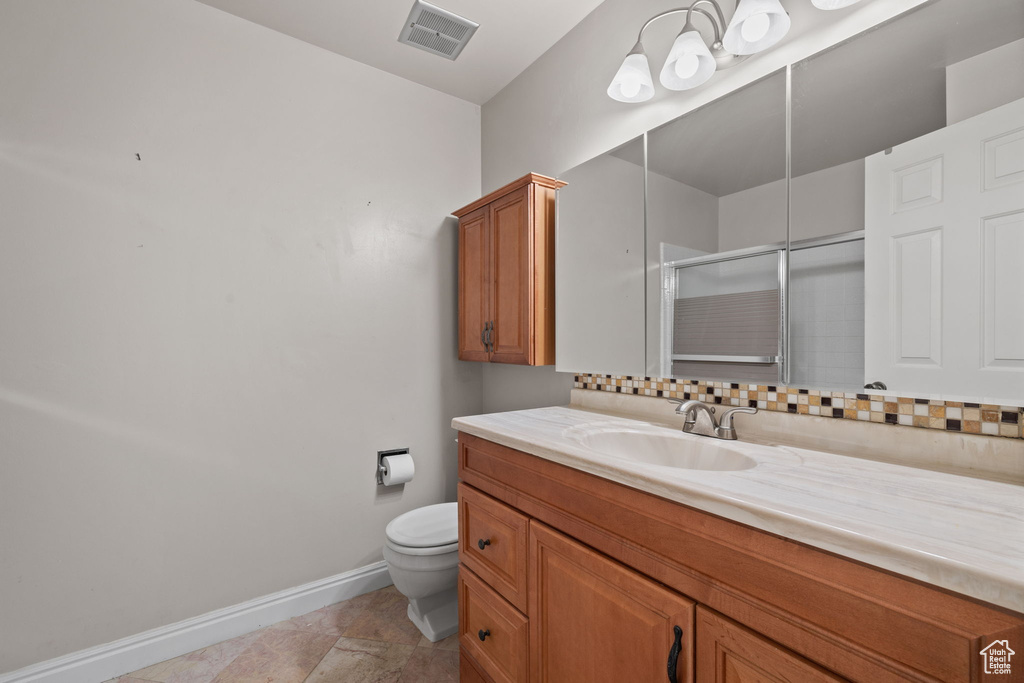 Bathroom with vanity, decorative backsplash, toilet, and walk in shower