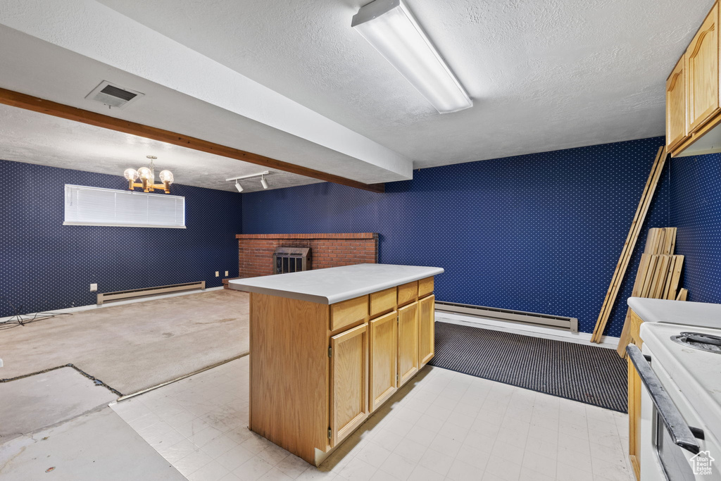 Kitchen with a baseboard heating unit, light brown cabinetry, pendant lighting, a center island, and white range