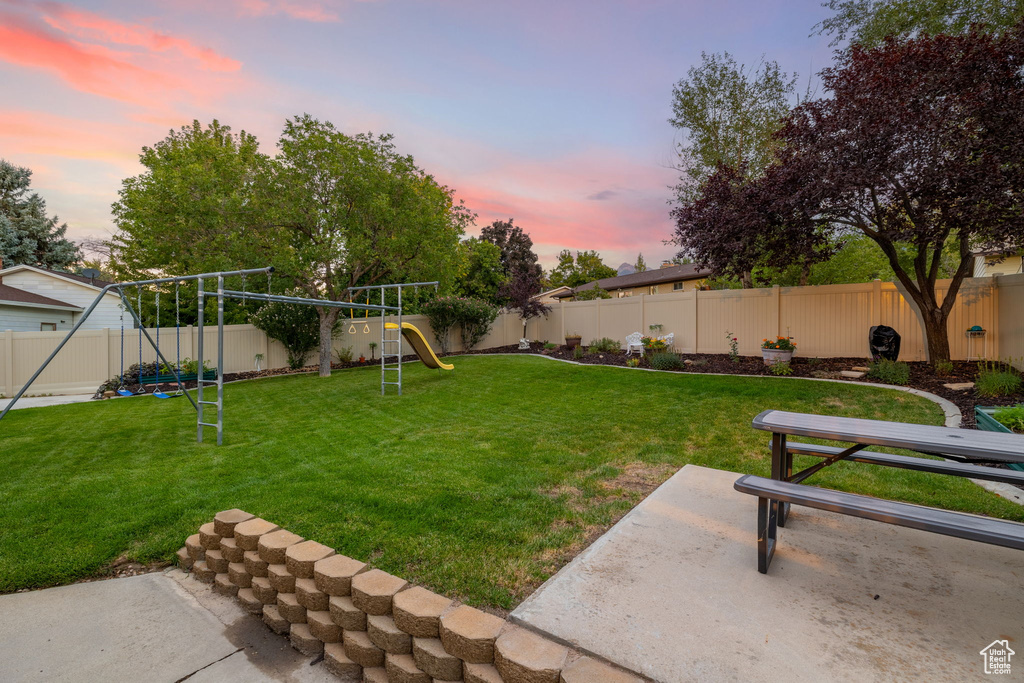 Yard at dusk featuring a patio area and a playground