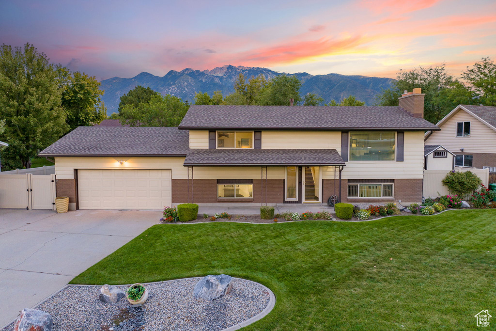 View of front of property with a mountain view, a lawn, and a garage