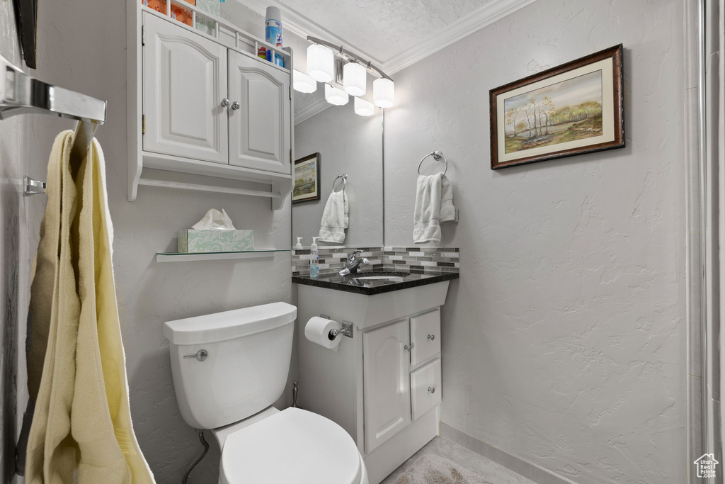 Bathroom with toilet, ornamental molding, vanity, and a textured ceiling