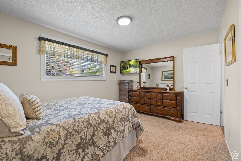 Bedroom featuring a textured ceiling and light colored carpet