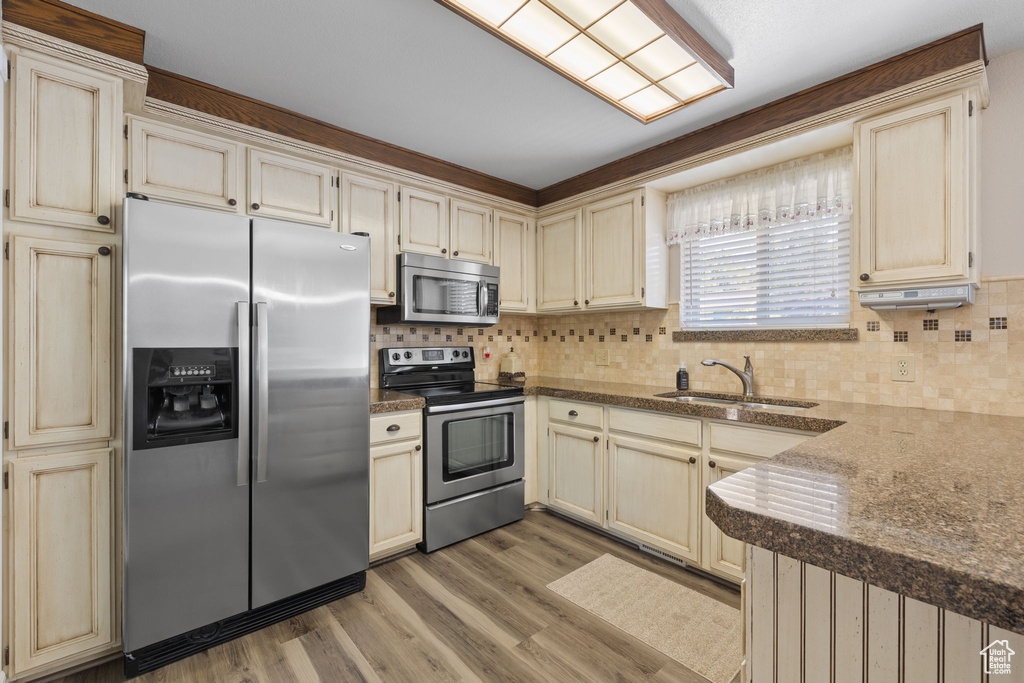 Kitchen featuring stainless steel appliances, sink, light wood-type flooring, and cream cabinetry