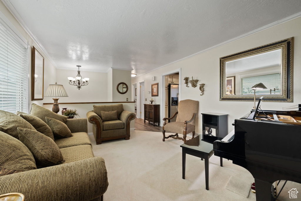 Living room featuring crown molding, a notable chandelier, a textured ceiling, and light colored carpet