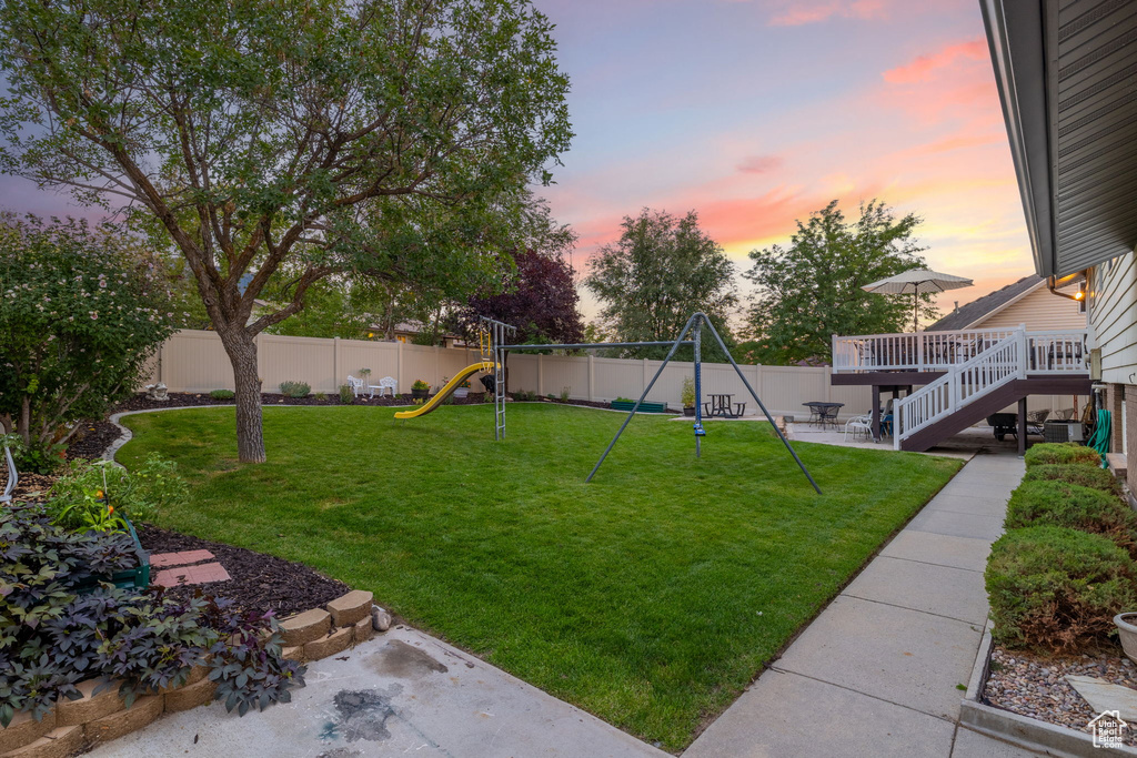 Yard at dusk featuring a deck and a playground