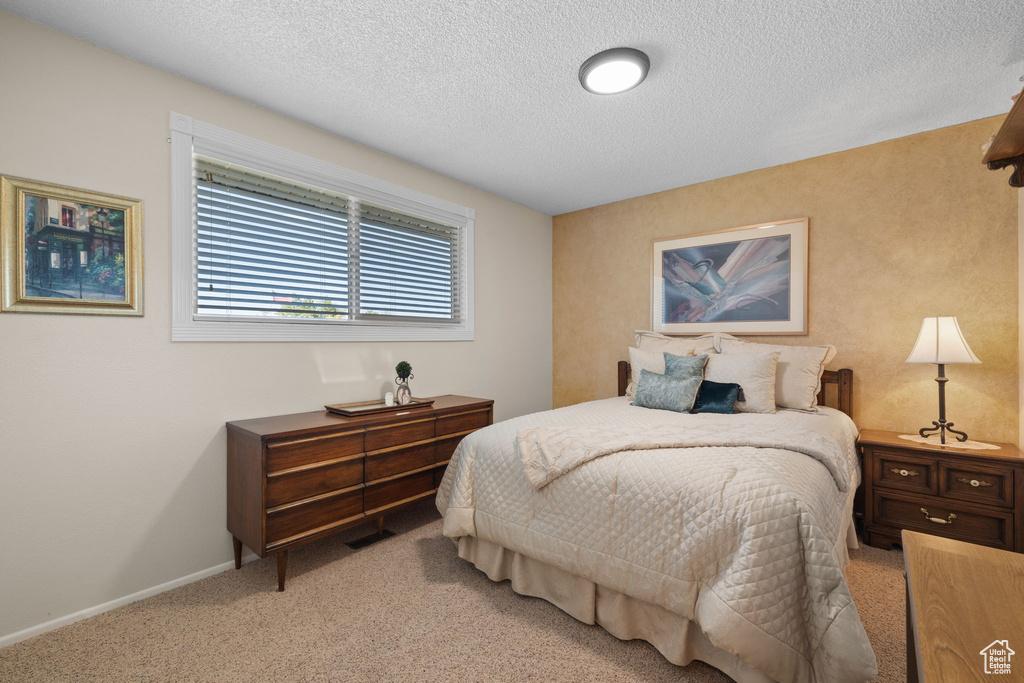 Bedroom featuring light carpet and a textured ceiling