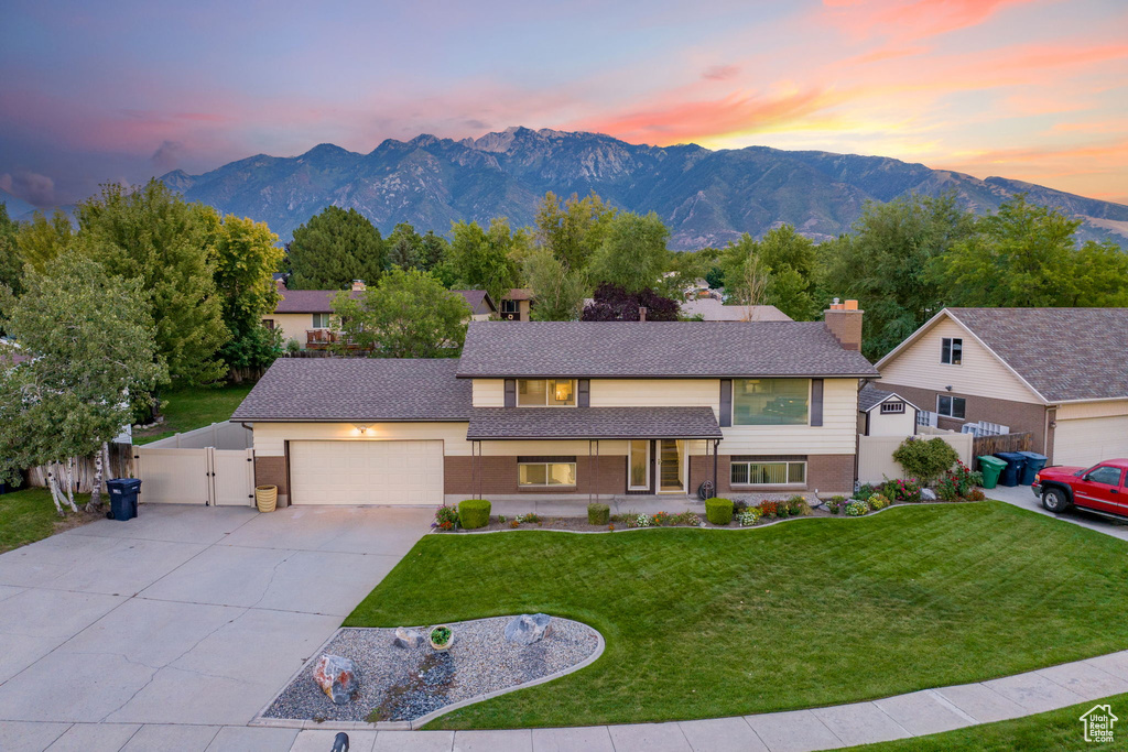 View of front of property with a mountain view, a garage, and a lawn