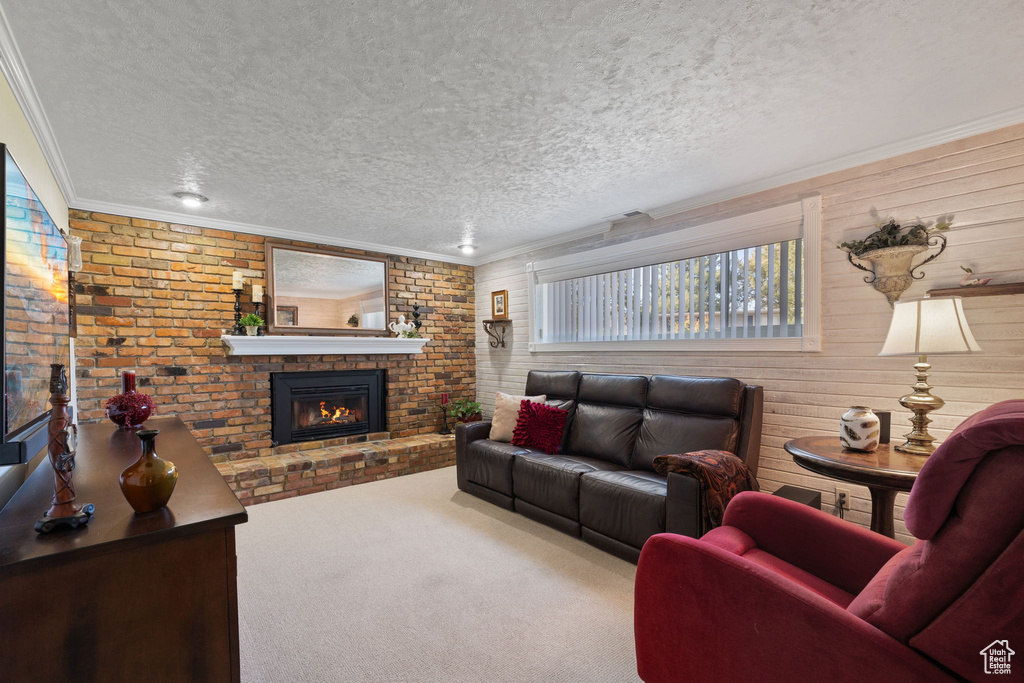 Living room featuring crown molding, a textured ceiling, brick wall, and carpet floors