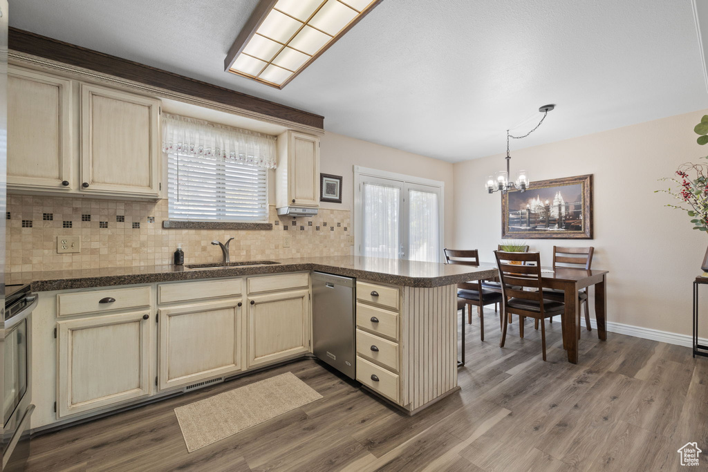 Kitchen with cream cabinetry, dark hardwood / wood-style floors, kitchen peninsula, stainless steel appliances, and sink