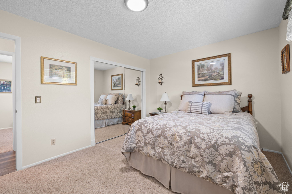 Carpeted bedroom featuring a textured ceiling and a closet