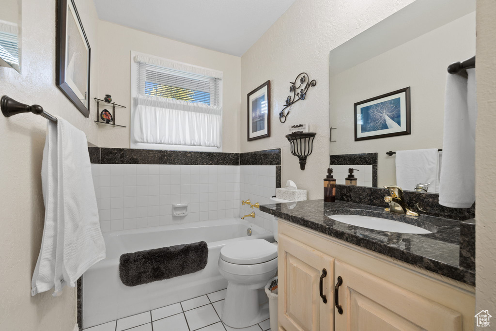 Bathroom featuring vanity, a bathing tub, toilet, and tile patterned flooring