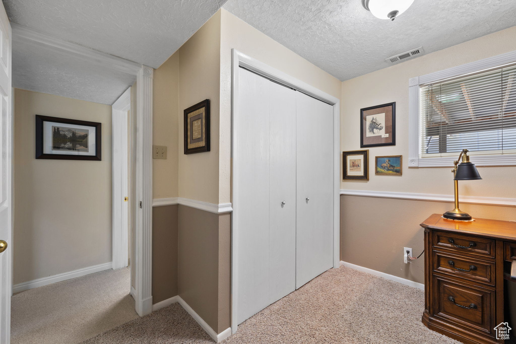 Interior space featuring a textured ceiling and light colored carpet