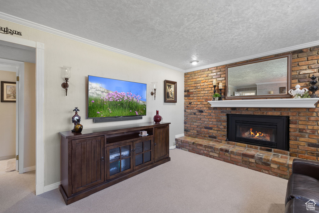 Carpeted living room with a textured ceiling, ornamental molding, and a brick fireplace