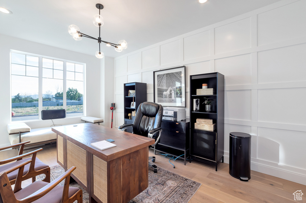 Office area with light hardwood / wood-style floors and a chandelier