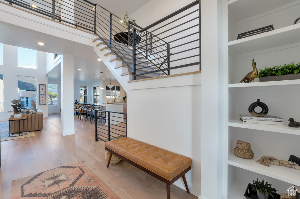 Stairs with built in features, hardwood / wood-style floors, a high ceiling, and a wealth of natural light