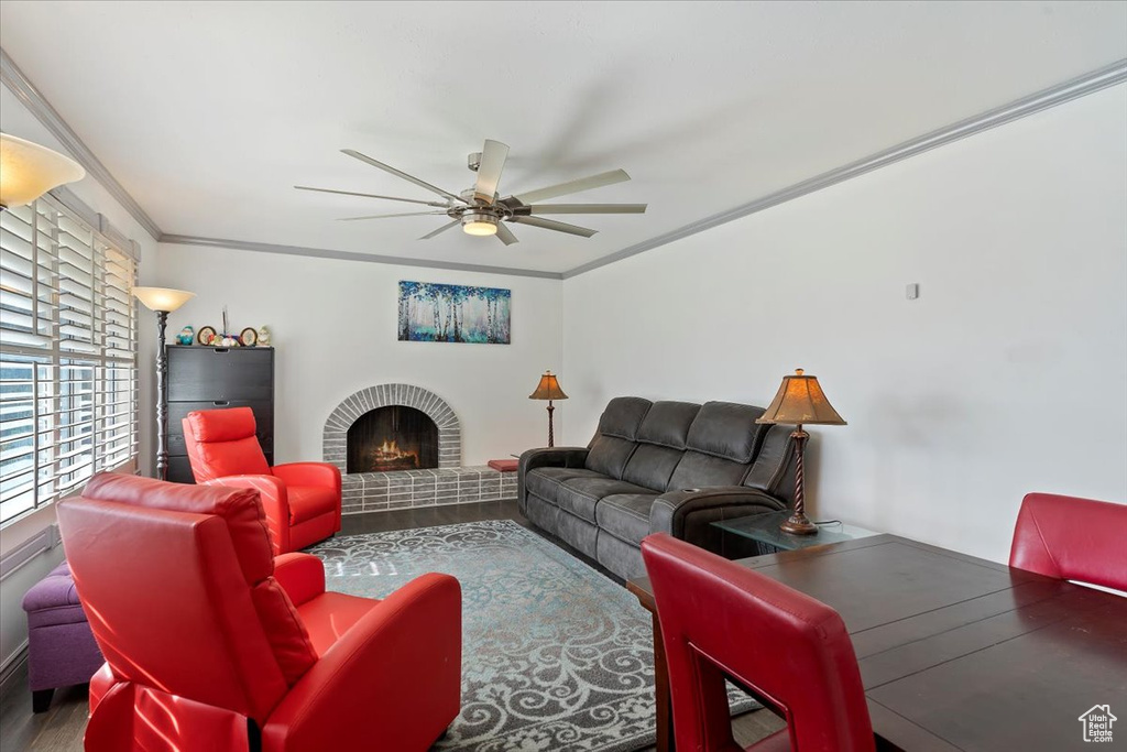 Living room featuring ornamental molding, wood-type flooring, a fireplace, and ceiling fan