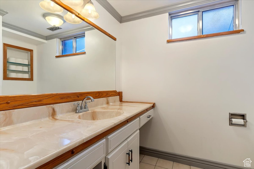 Bathroom with vanity, crown molding, a healthy amount of sunlight, and tile patterned floors