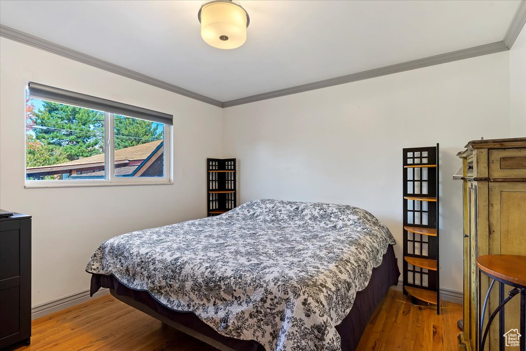 Bedroom featuring ornamental molding and hardwood / wood-style flooring