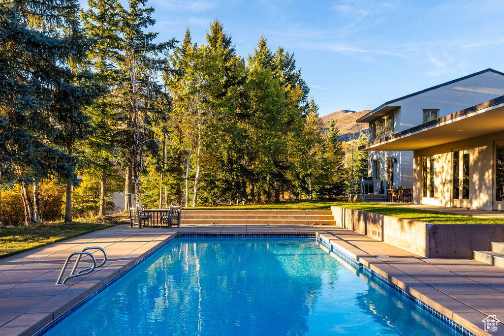 View of pool with a mountain view and a patio area