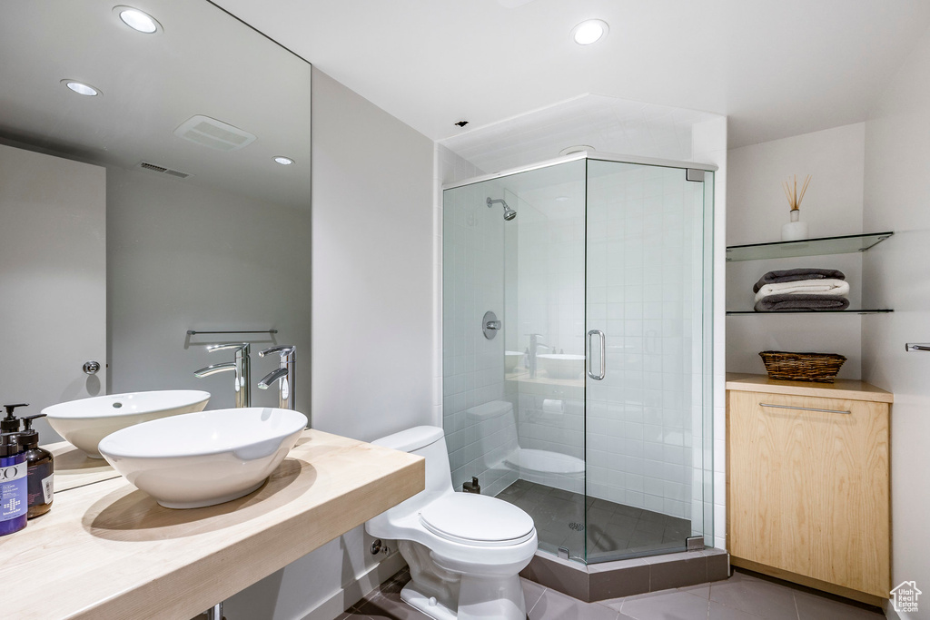 Bathroom with tile patterned flooring, toilet, an enclosed shower, and sink