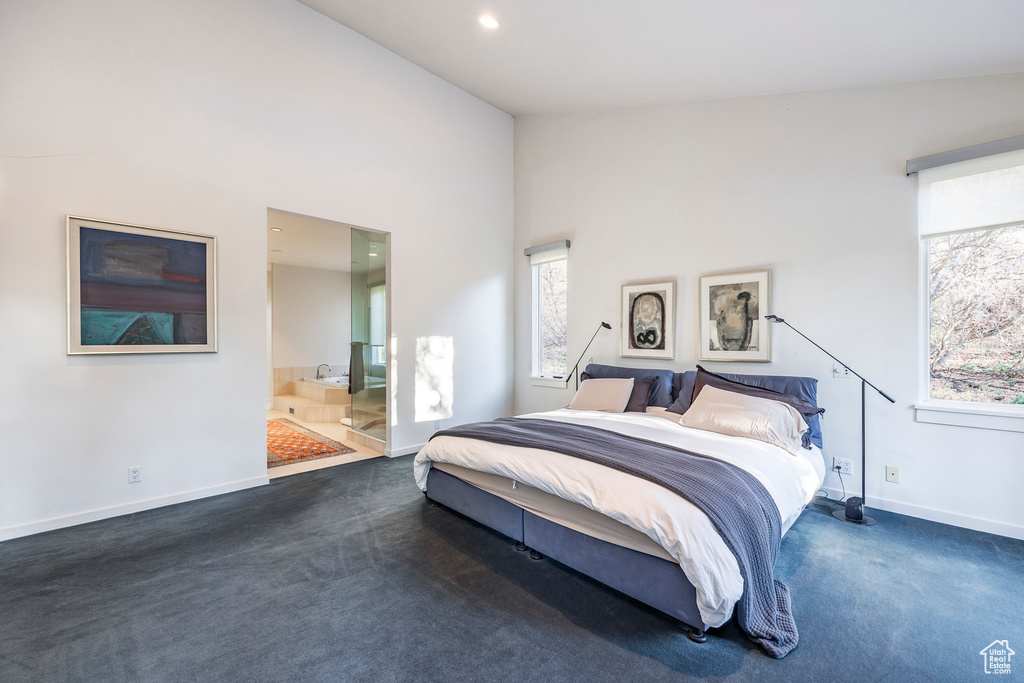 Carpeted bedroom with connected bathroom and high vaulted ceiling