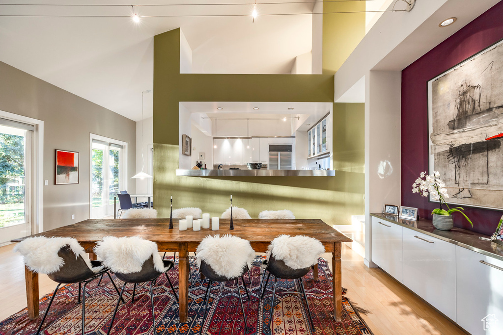 Dining area with track lighting, light hardwood / wood-style flooring, and high vaulted ceiling