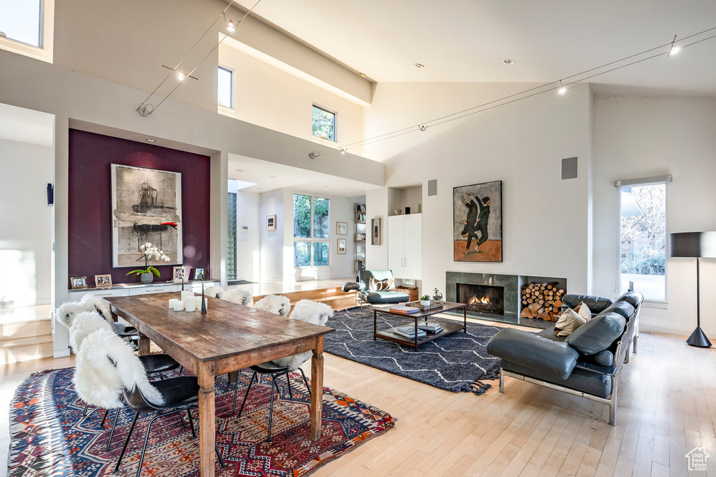 Dining space featuring high vaulted ceiling, light wood-type flooring, and rail lighting