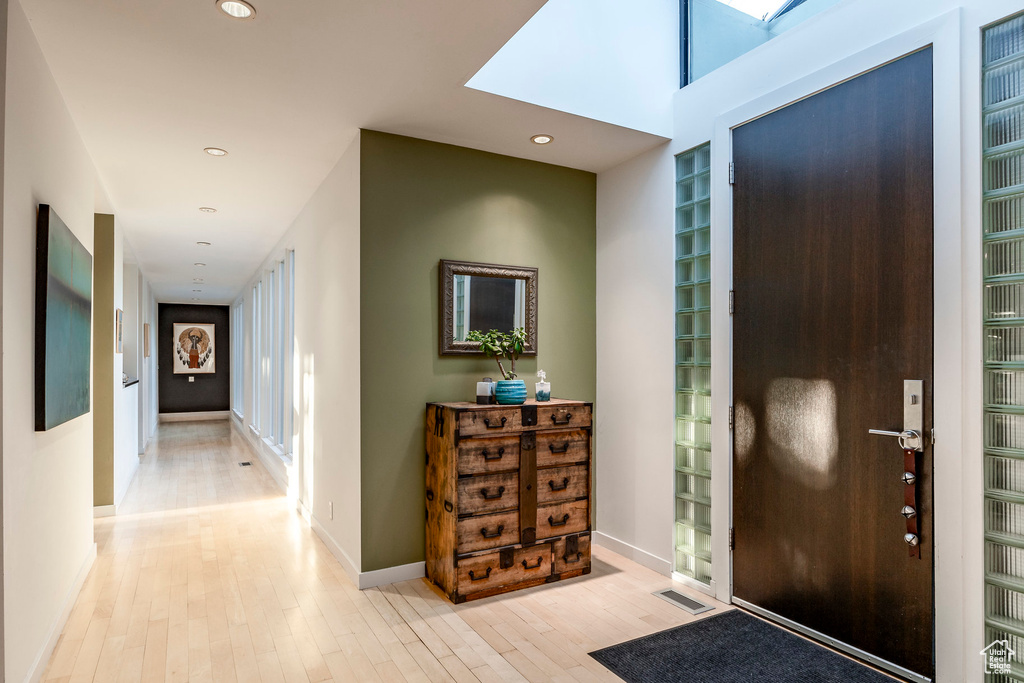 Entrance foyer with a skylight and light hardwood / wood-style floors