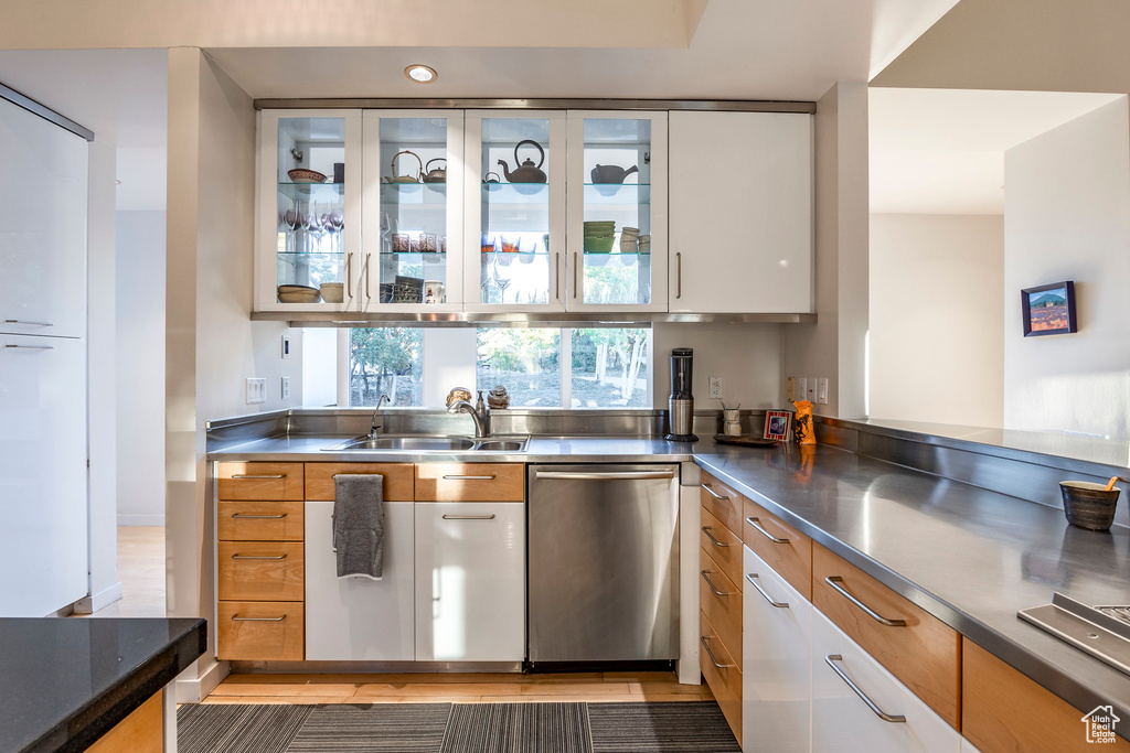 Kitchen featuring stainless steel dishwasher, white cabinetry, sink, and stainless steel counters