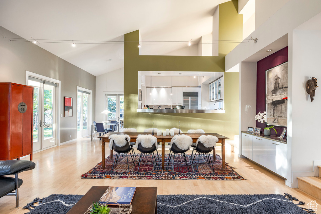 Dining area featuring high vaulted ceiling and light wood-type flooring