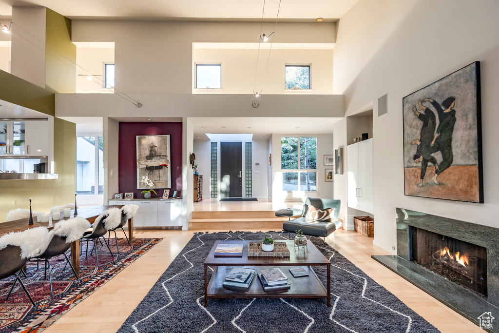 Living room with a fireplace, light hardwood / wood-style flooring, and a high ceiling