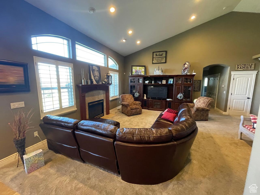 Carpeted living room featuring high vaulted ceiling and a tile fireplace