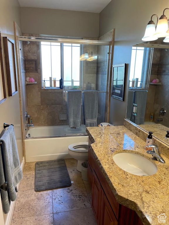 Full bathroom featuring vanity, toilet, and bath / shower combo with glass door