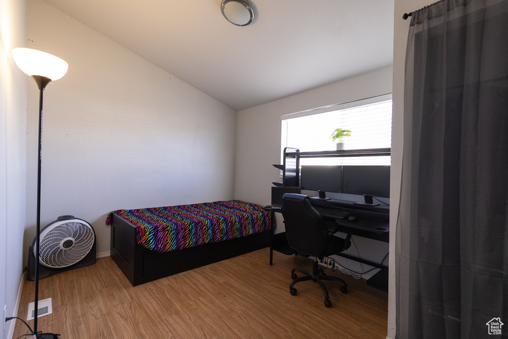 Bedroom with lofted ceiling and light wood-type flooring