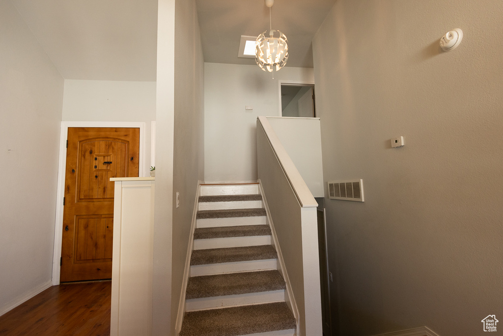 Stairway featuring hardwood / wood-style flooring and an inviting chandelier