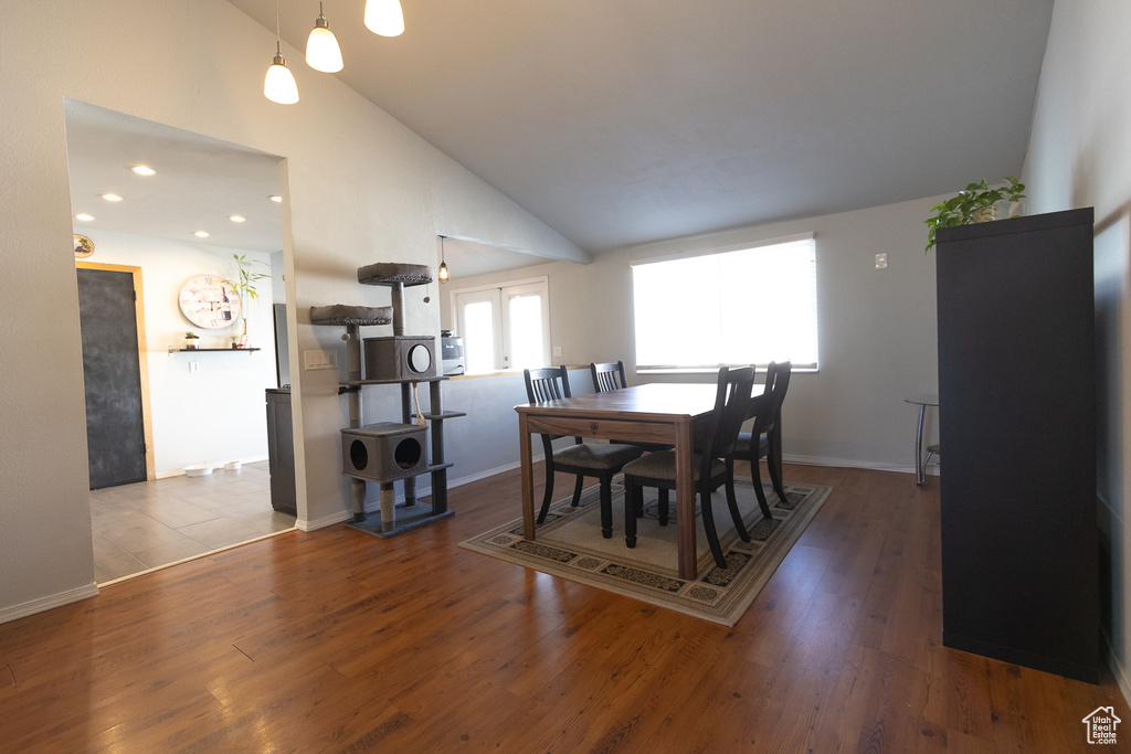 Dining area with french doors, high vaulted ceiling, and hardwood / wood-style floors