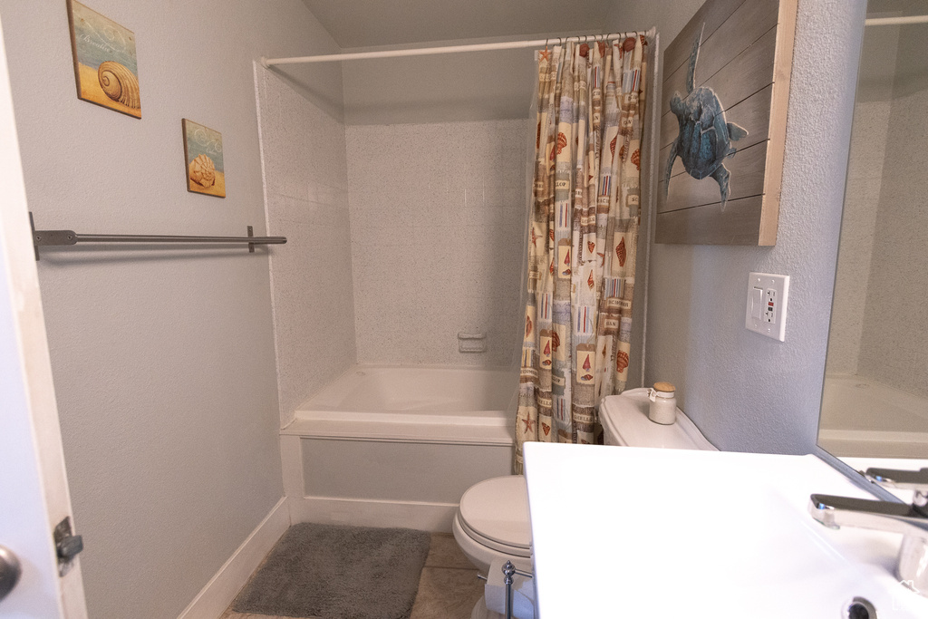 Bathroom featuring toilet, shower / bath combination with curtain, and tile patterned floors